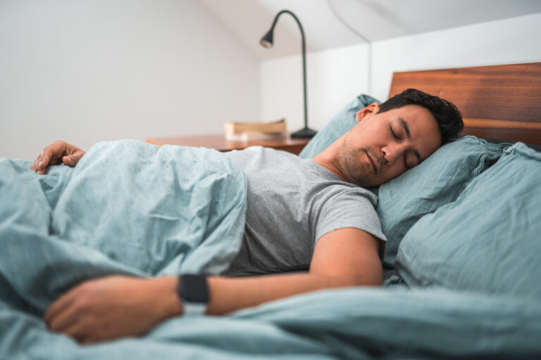Biracial Man Sleeping in Bed With Watch